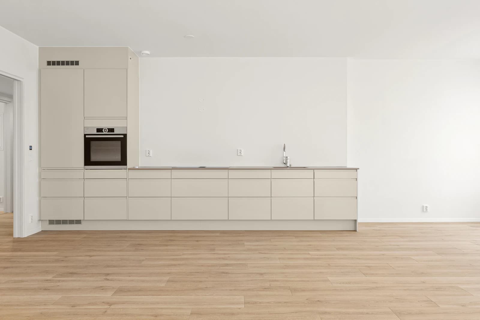 An unfurnished apartment kitchen and adjoining living area